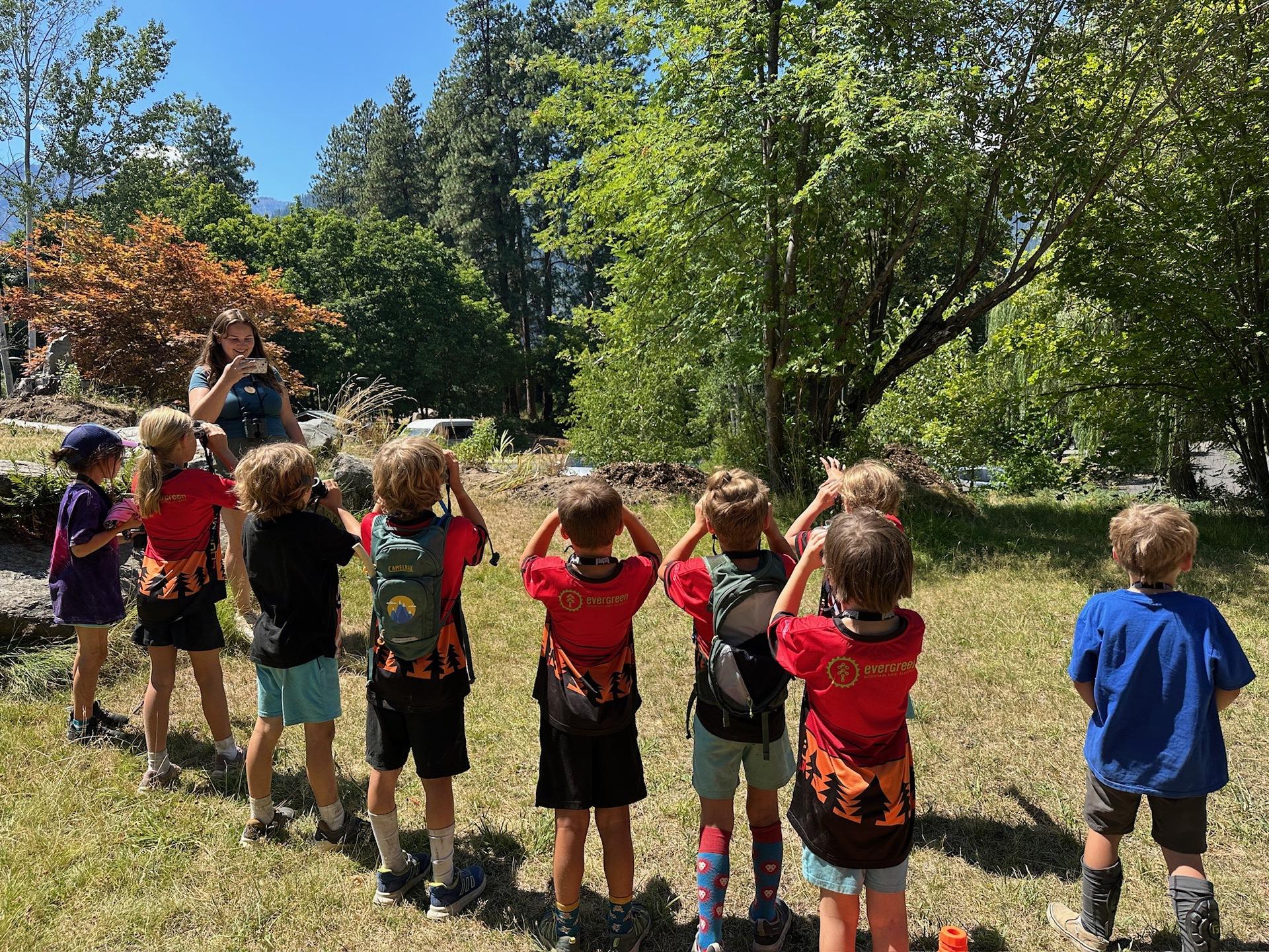 Picture of kids looking at bird through binoculars at a summer camp.