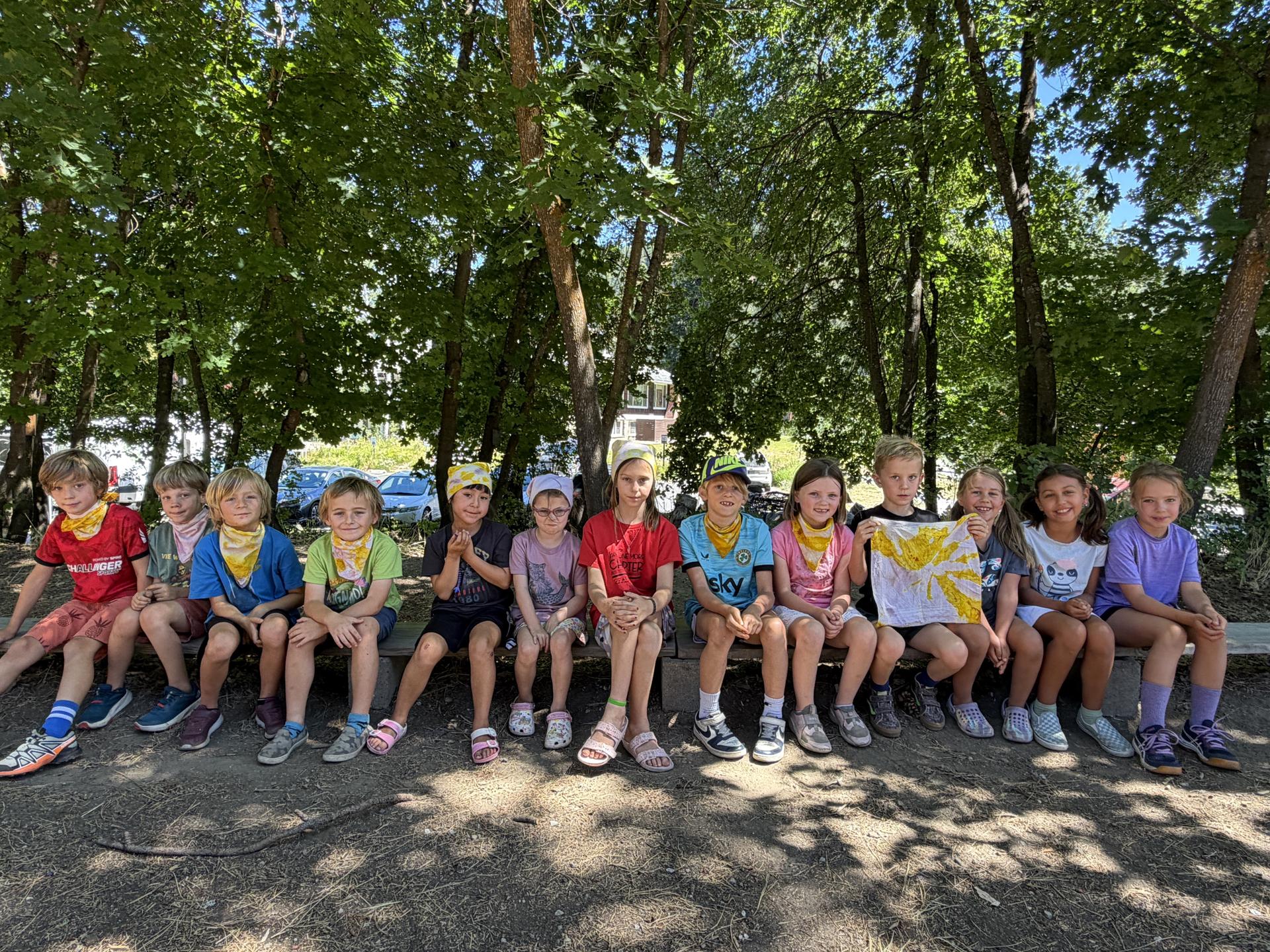 WRI Soil to Snack campers lined up sitting on a log outside for a group photo.