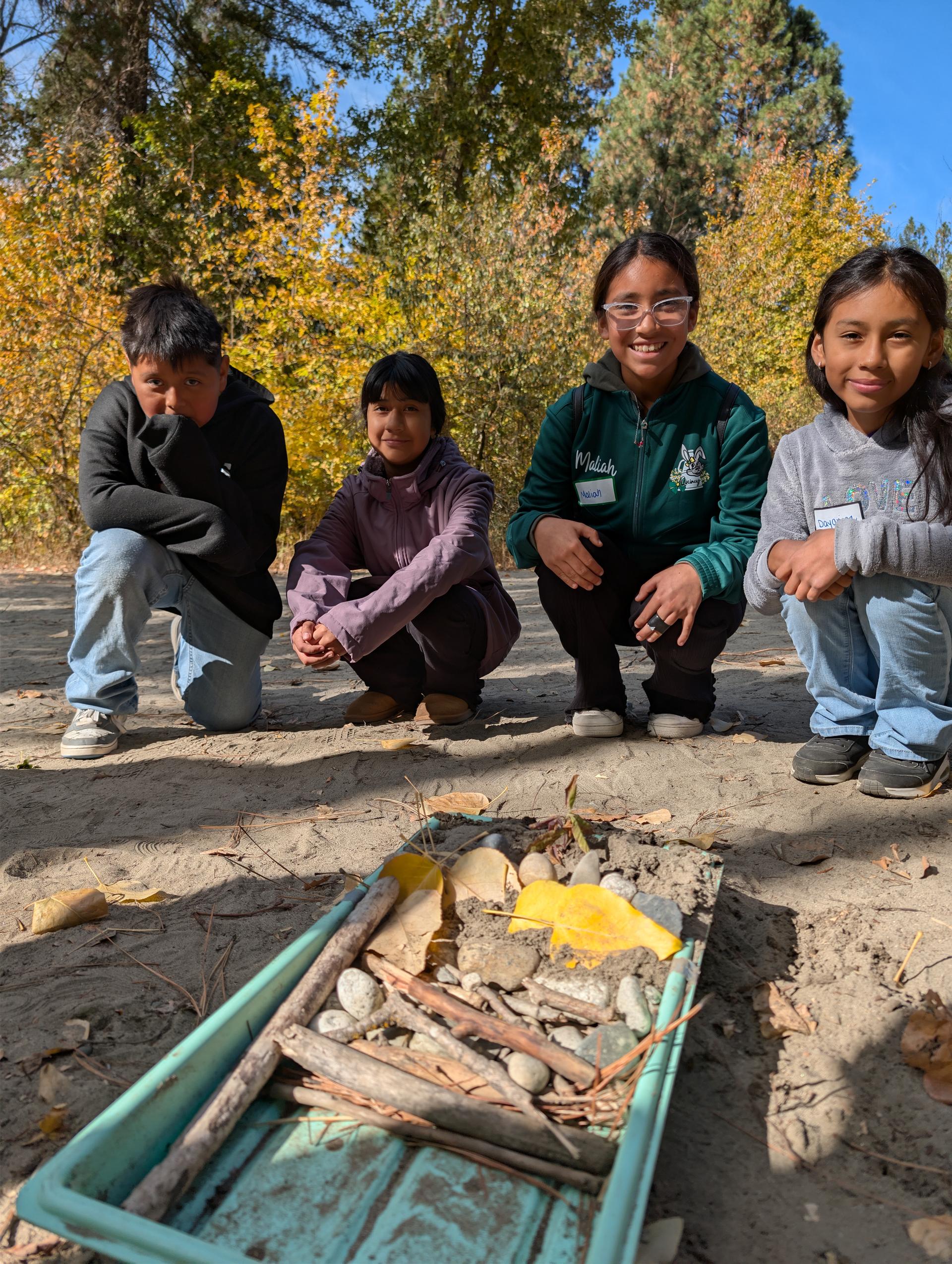 Image of four students testing out erosion control experiment as part of WRI Field Days.