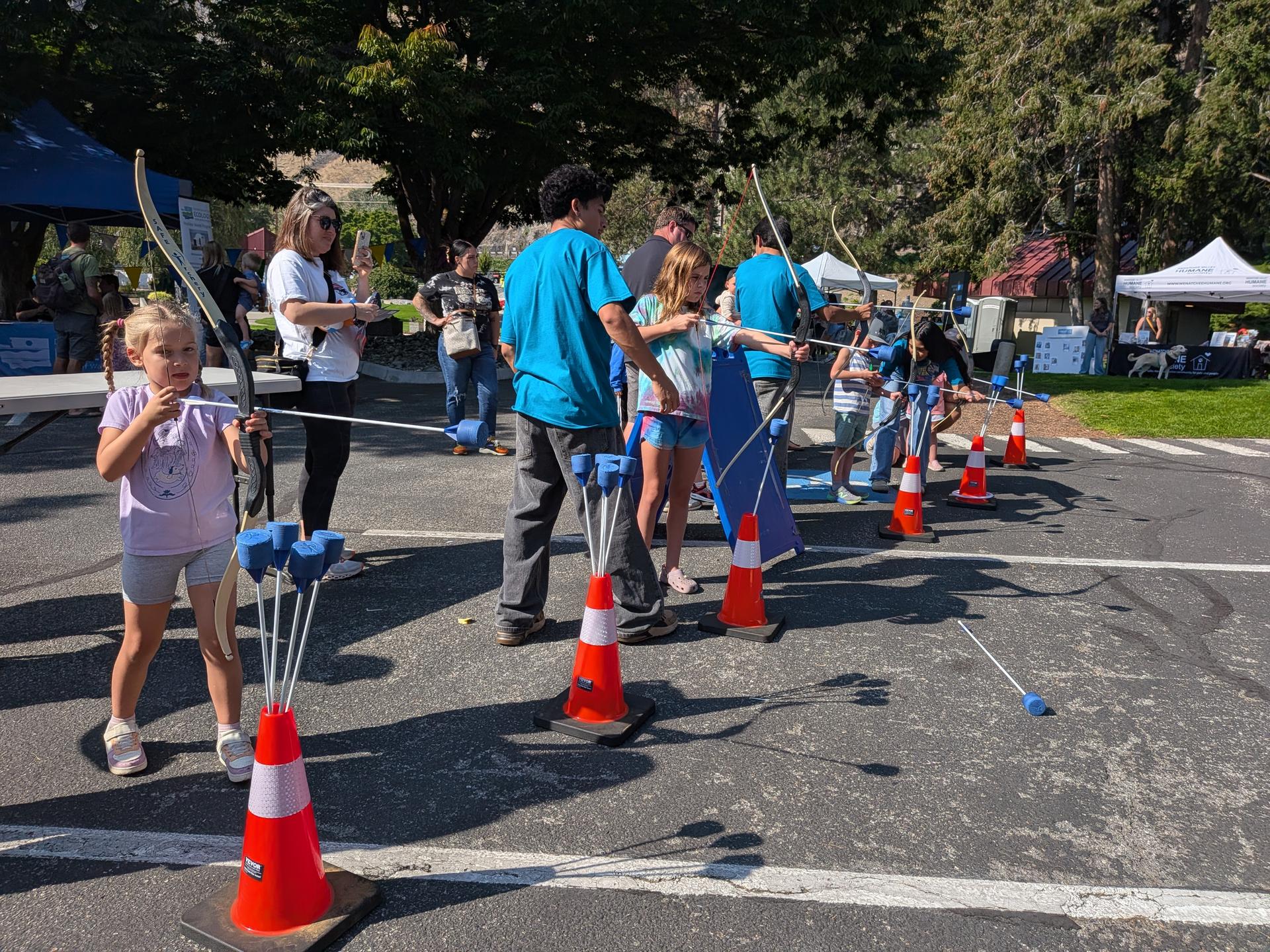 Kids at the 2026 Salmon Fest at Rocky Reach Dam trying the inflatable archery with Wenatchee River Institute.