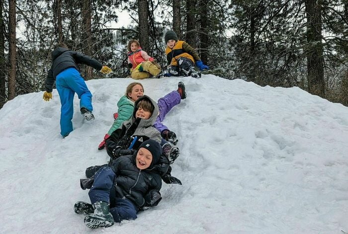 A picture of kids at WRI sledding down a pile of snow.