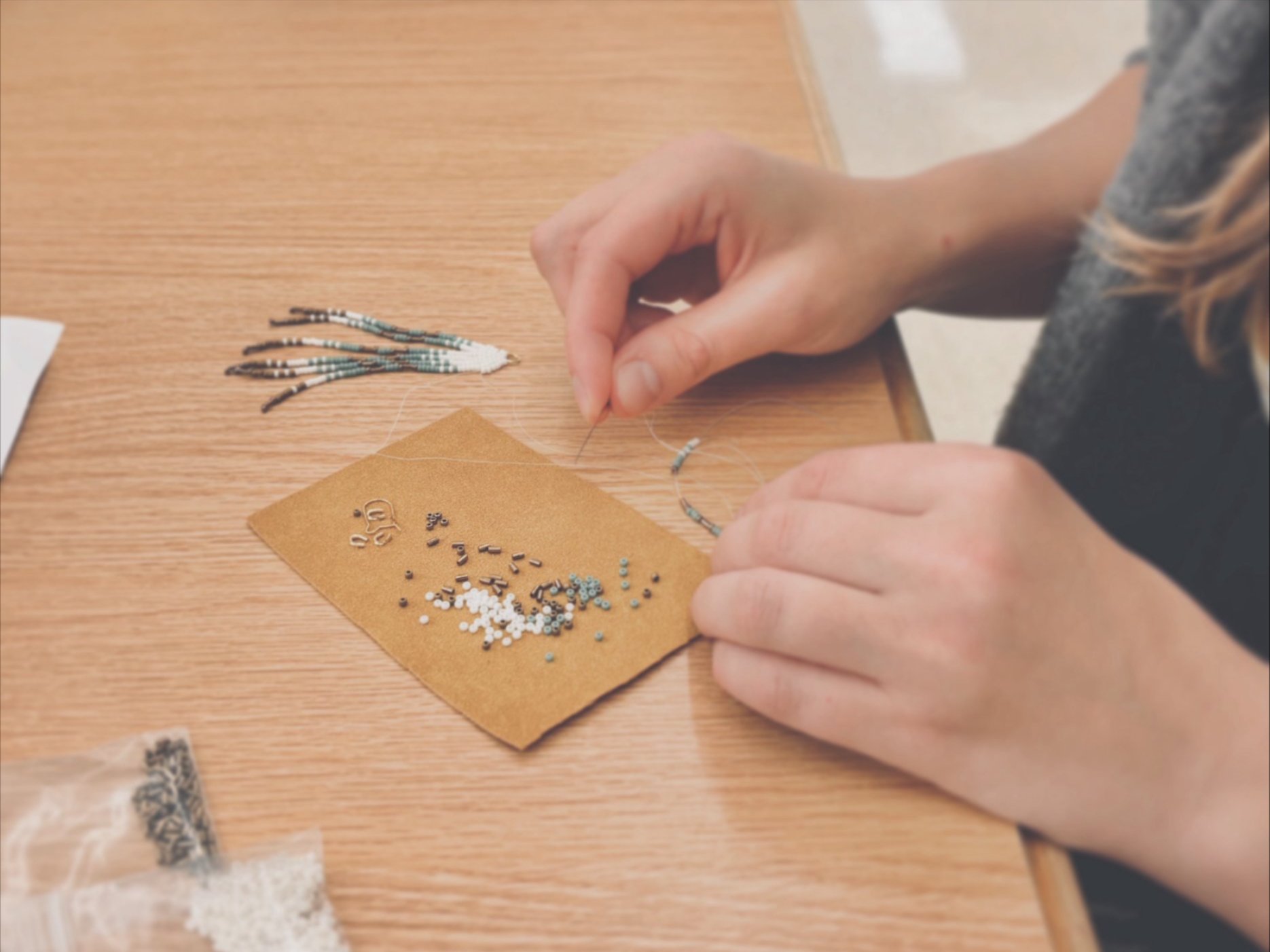 An image of a woman working on a mini fringe earring with beadwork.