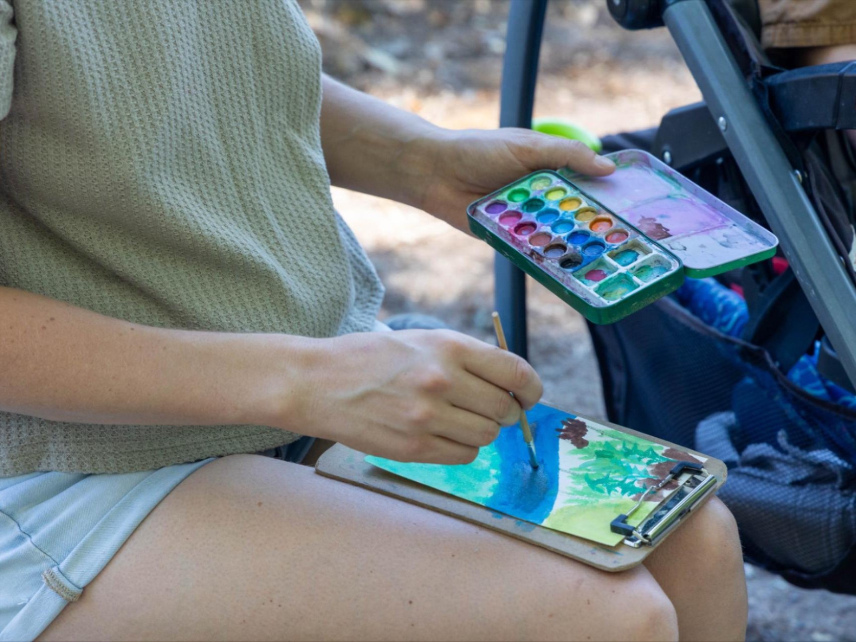 A participant painting  river and trees during Wenatchee River Institute's Paint Stroll