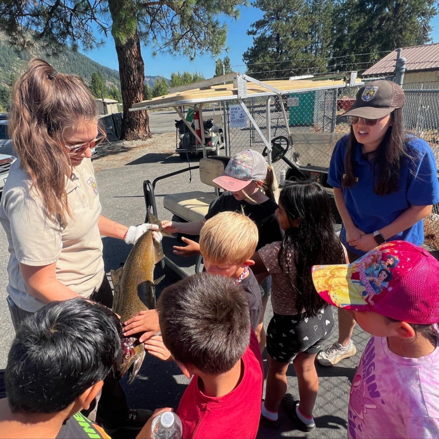 Image of Leavenworth National Fish Hatchery workers showing kids a salmon.