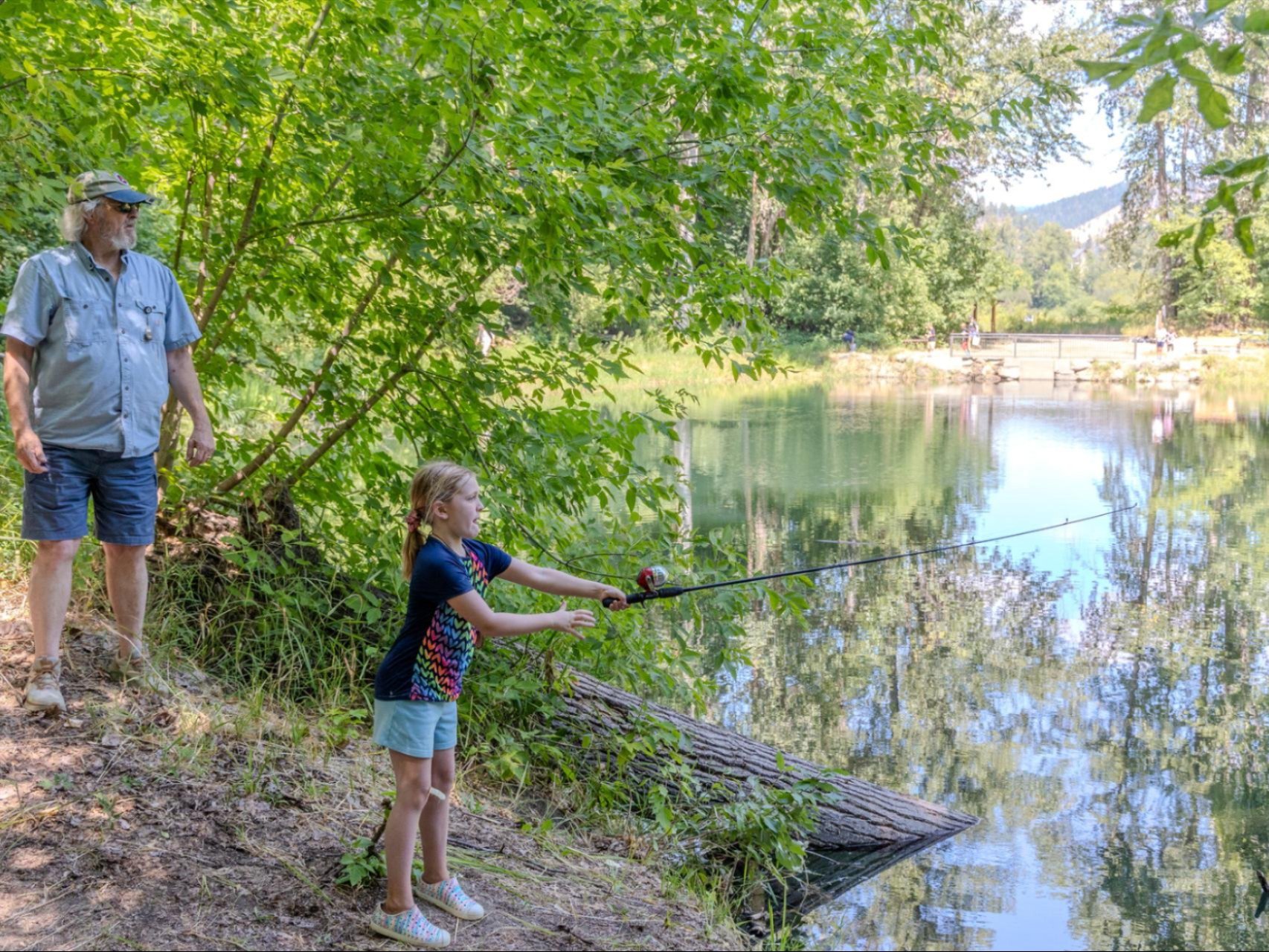 A Kids in the Wild camper fishing in the Blackbird Island Pond with Trout Unlimited member