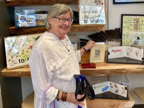 Photo of Carleen Ormbrek Zimmerman with her bird artwork on display.