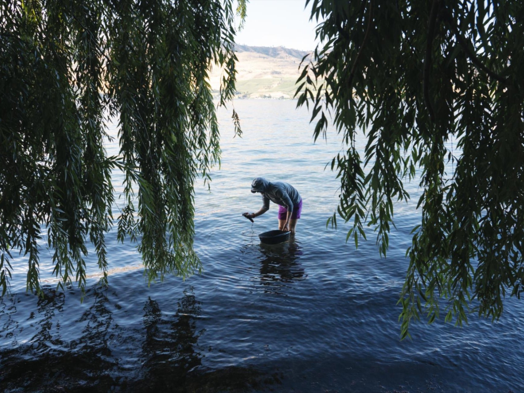 Image of Cristina Barone standing on a beach with water and mountains in the background.