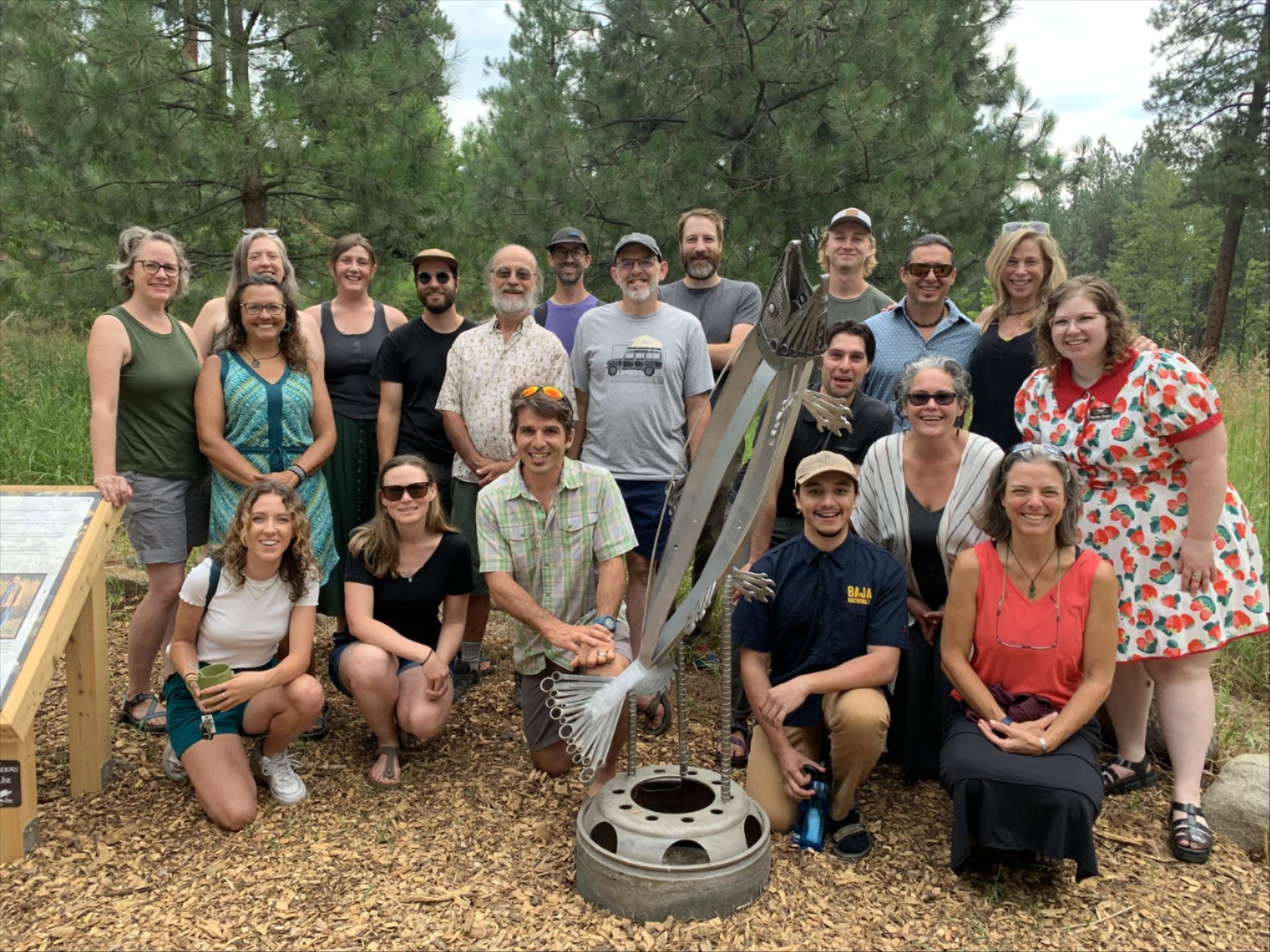 Picture of men and women that are the Wenatchee River Institute Staff and Board of Directors in 2023 standing behind a salmon metal sculpture.