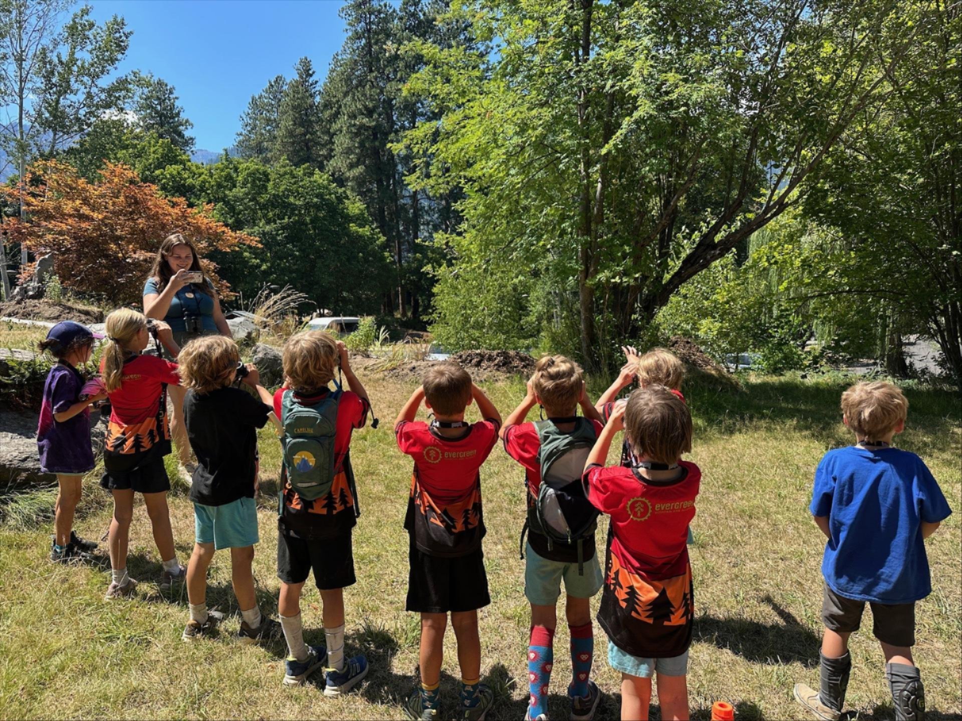 Summer camp for Bike & Explore. A row of kids using binoculars at Wenatchee River Institute.