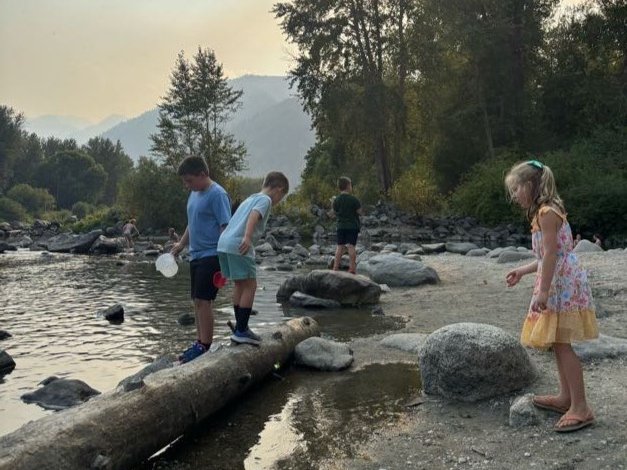 Kids walking on a log by the Wenatchee River during an After School Program.