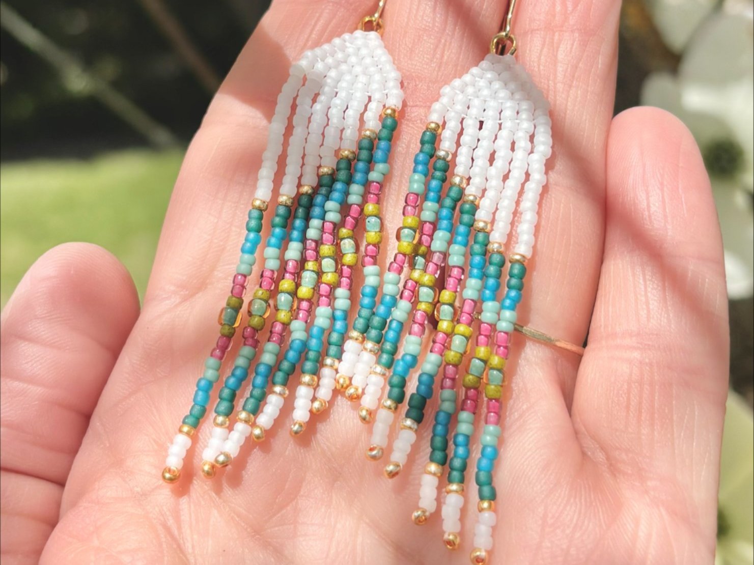 An image of a woman working on a mini fringe earring with beadwork.